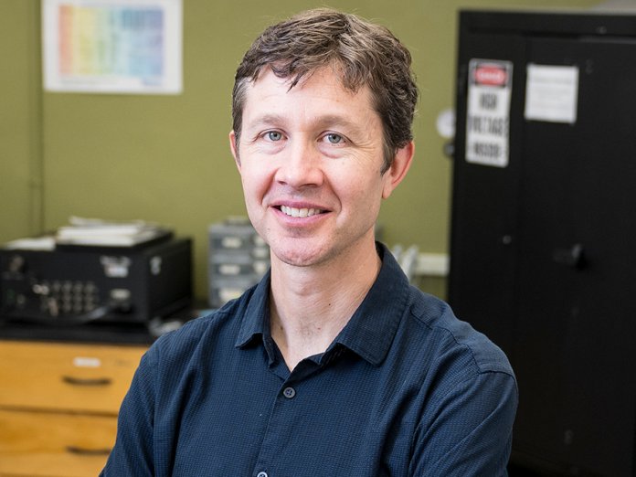 Headshot of Ethan Minot smiling in the optics lab