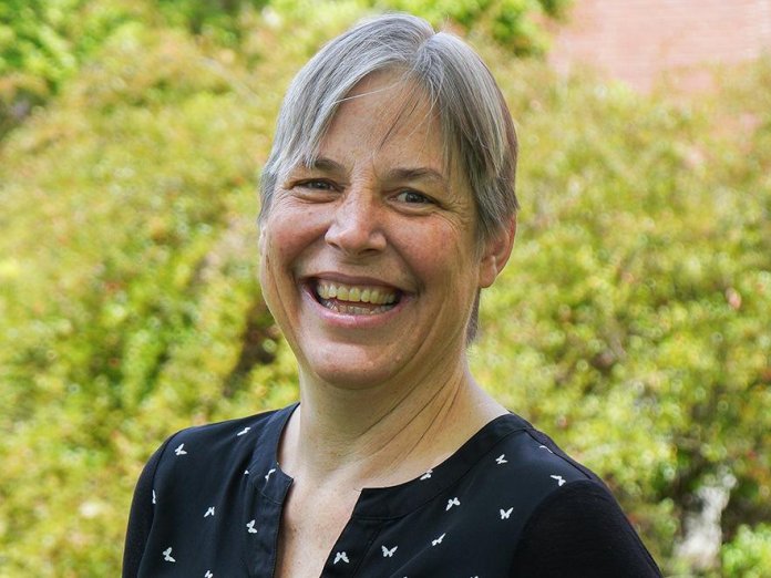 Kari van Zee smiles broadly in a campus headshot