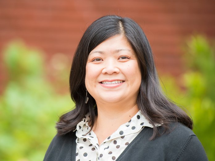 Maureen Leong-Kee smiling in front of a building on campus