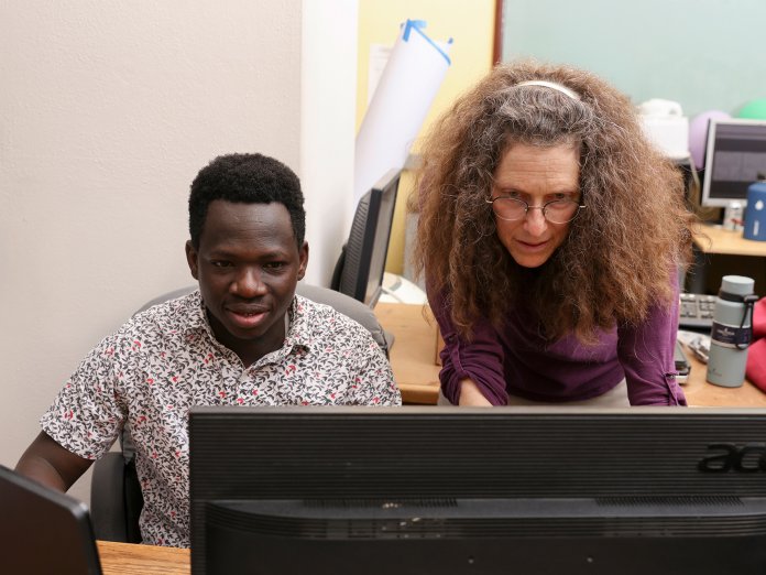 A professor and graduate student focus intensely on a computer screen as they work together.