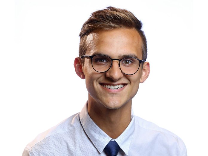 Smiling headshot of a man in a button up and tie