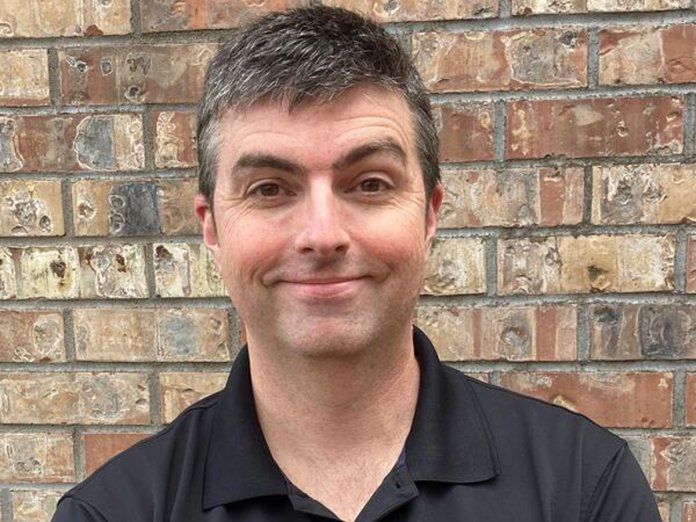 Smiling man standing in front of a brick wall