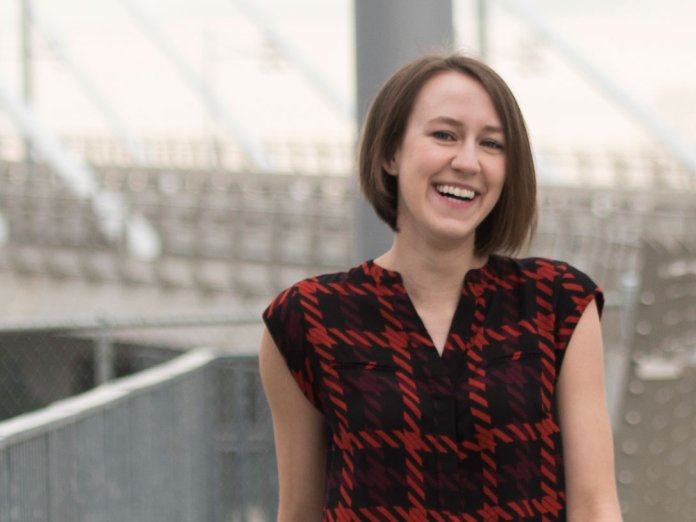 A woman in plaid laughs, standing on a bridge