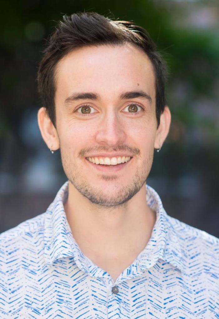 Bryan Lynn smiles for a headshot photo in a button-up shirt.