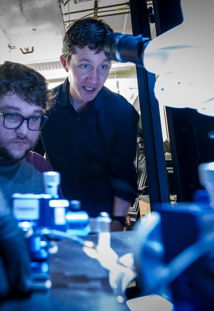 A professor shows a student how to use a piece of lab technology.