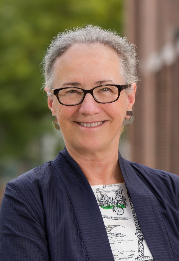 Portrait of woman smiling at camera, wearing blue blazer and glasses