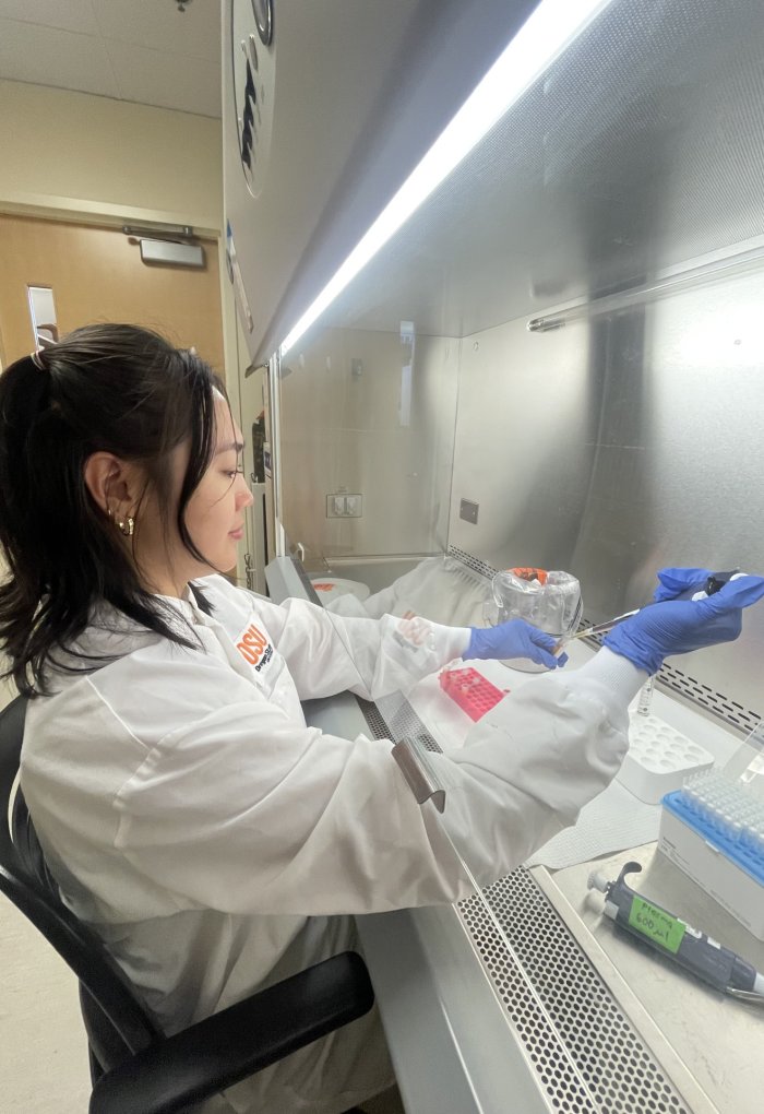 A woman in a lab coat works with a pipet.