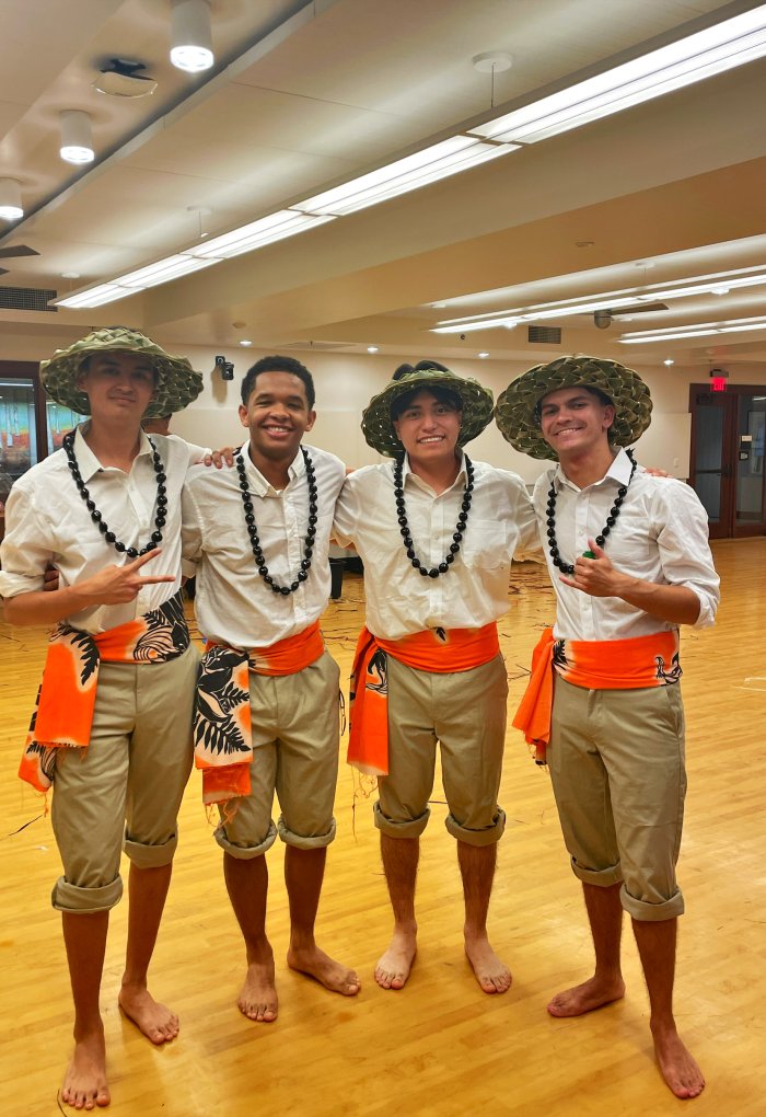 Four men pose for a photo wearing pacific islander clothing.