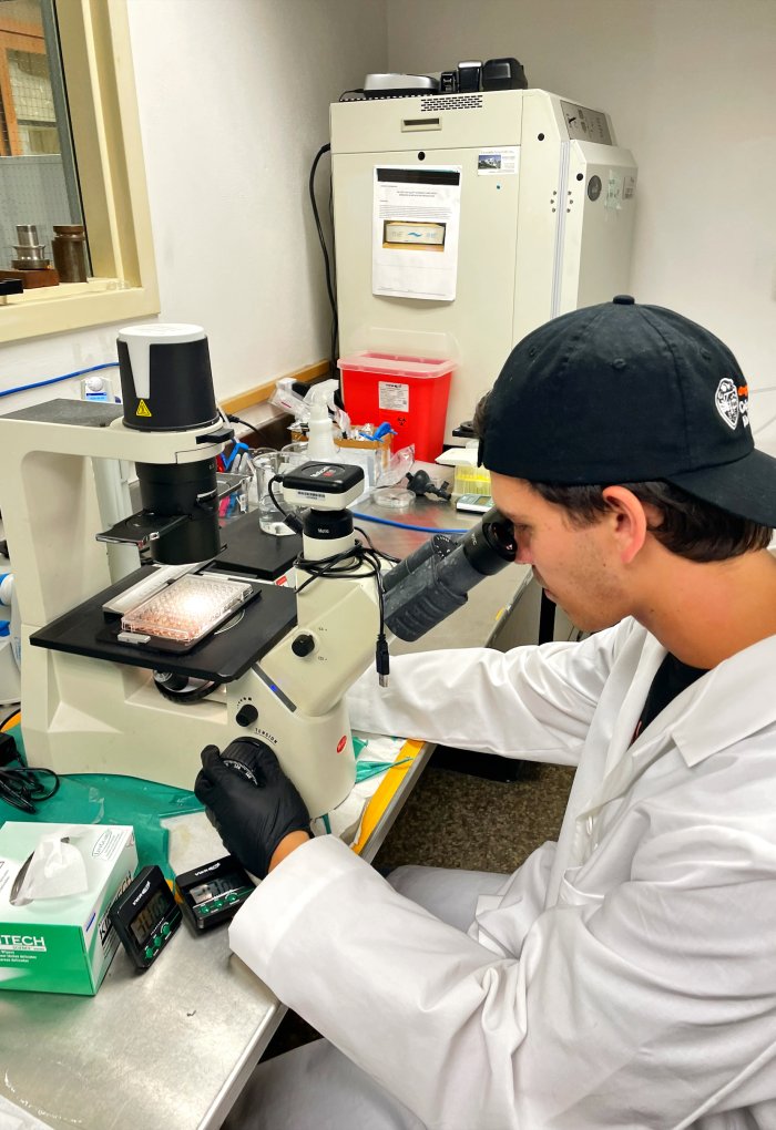 A man in a backwards hat works at a lab.