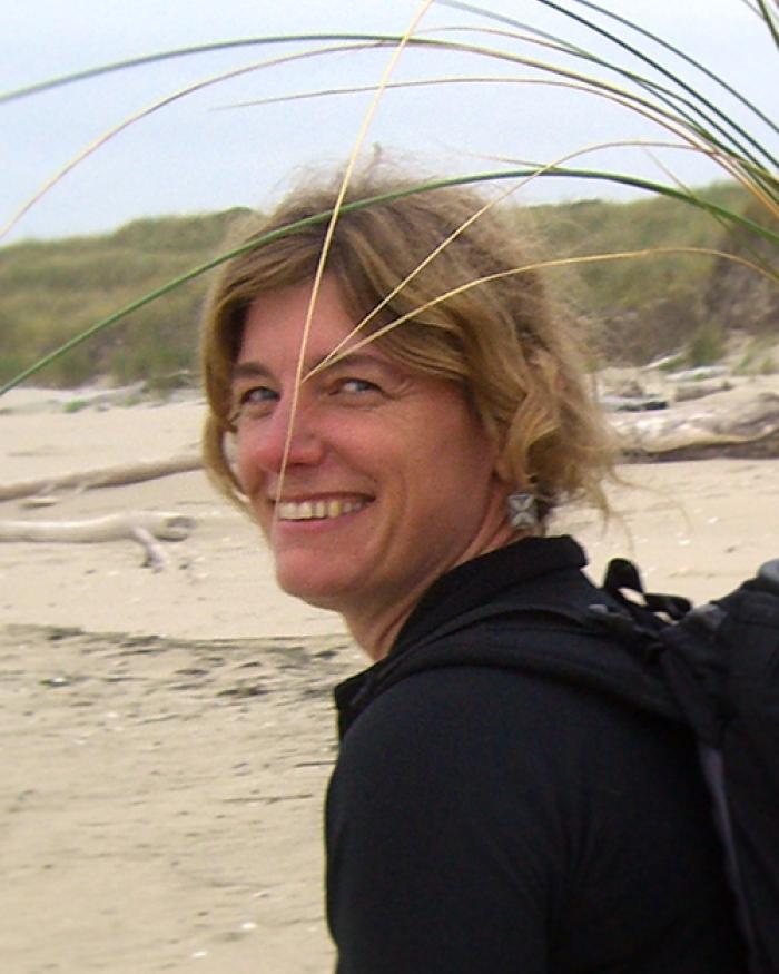 Sally Hacker walking along beach with grass samples in backpack