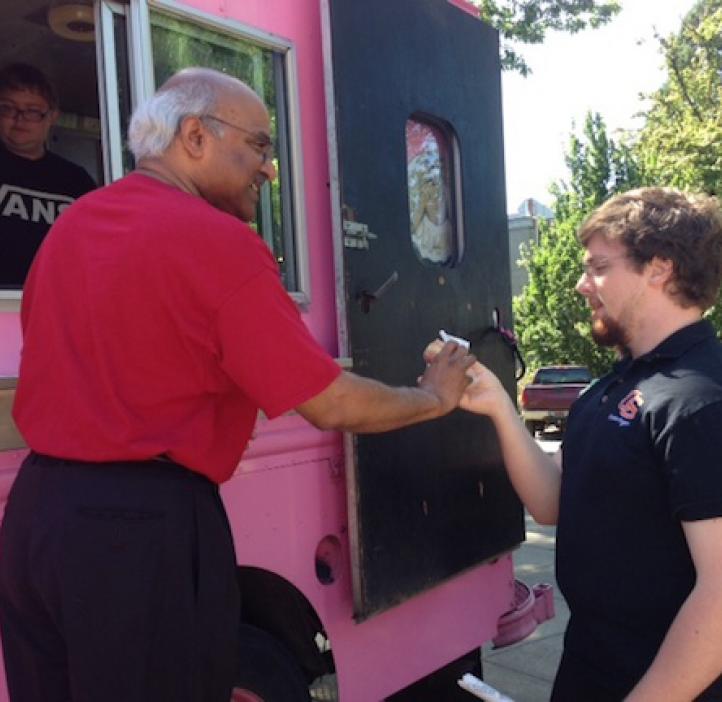 student grabbing donut from pink delivery truck