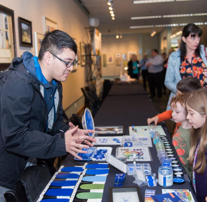 Pigment researcher telling kids about blue pigment at booth