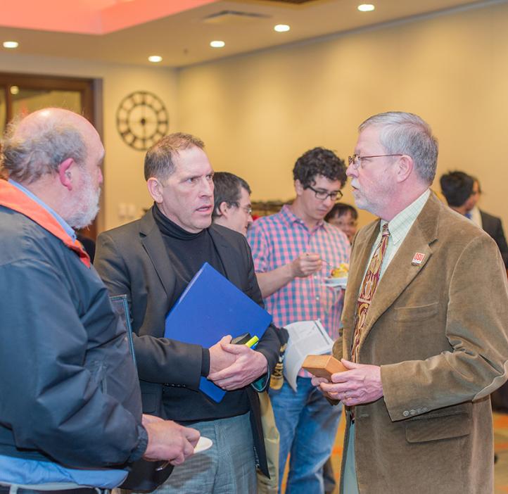 Matt Andrews and faculty chatting in lobby