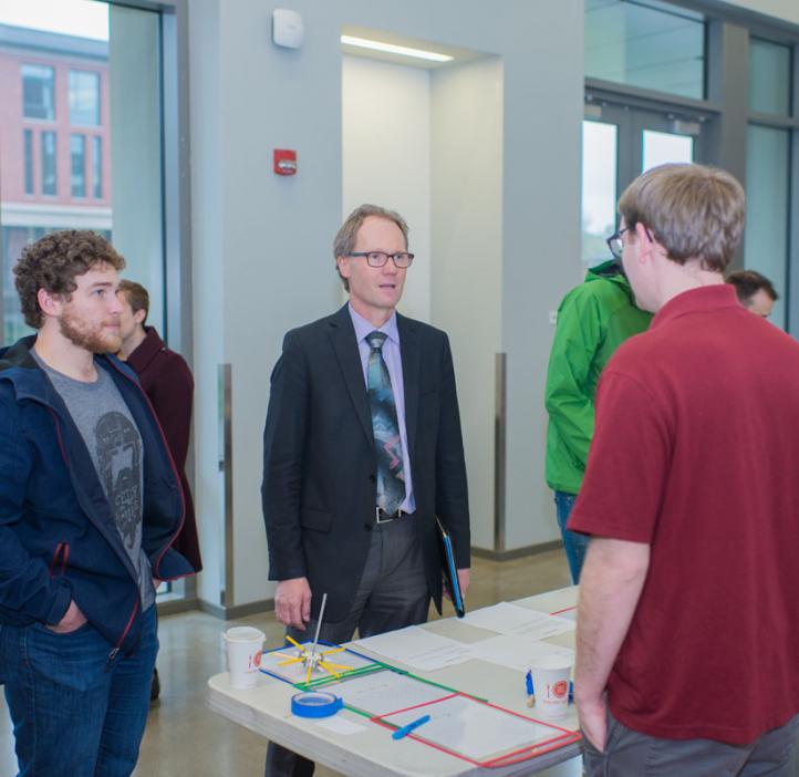 students demonstrating experiment to Roy Haggerty at club booth