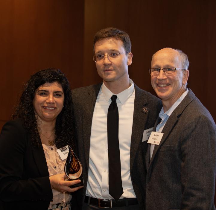 Justin Hall hugging Elisar Barbar and Andy Karplus next to stage