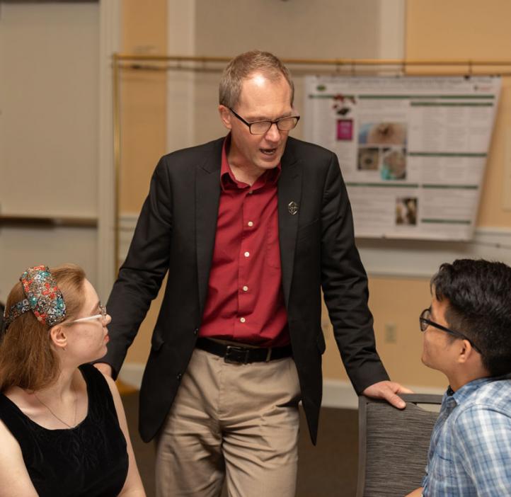 Roy Haggerty speaking with students at table