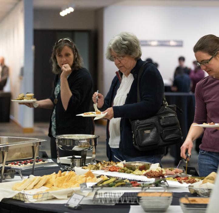faculty grabbing food at event table