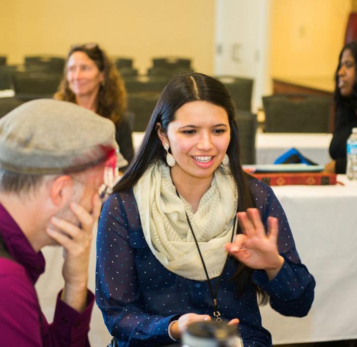 female conference attendee talking with colleagues at table