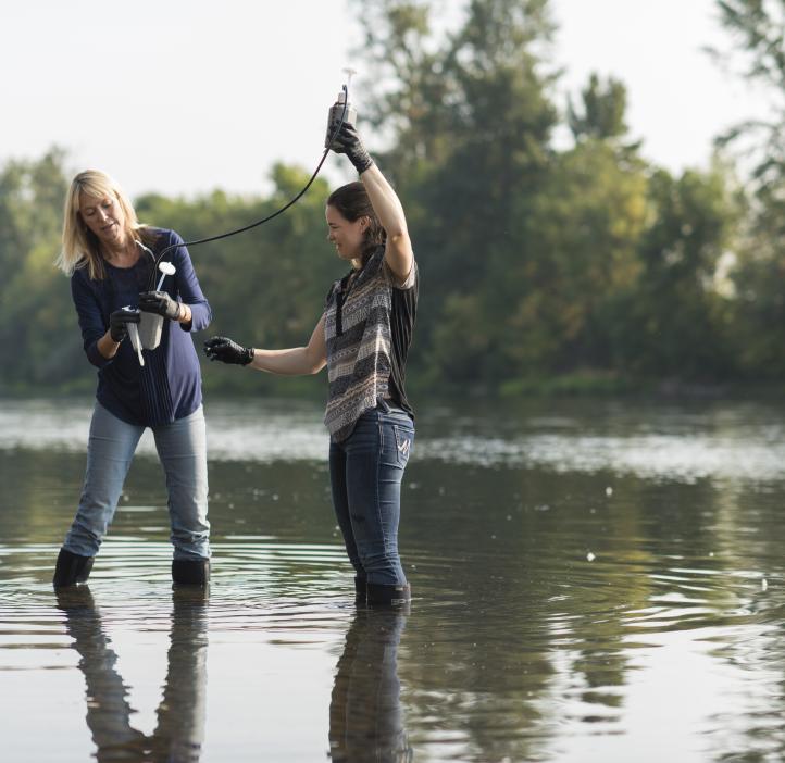 Kim Halsey with graduate student taking samples from a river