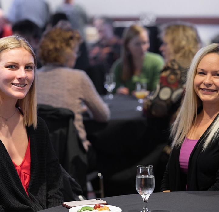 Alex Beck and student Jayden Rummell smile for photographer while sitting at table