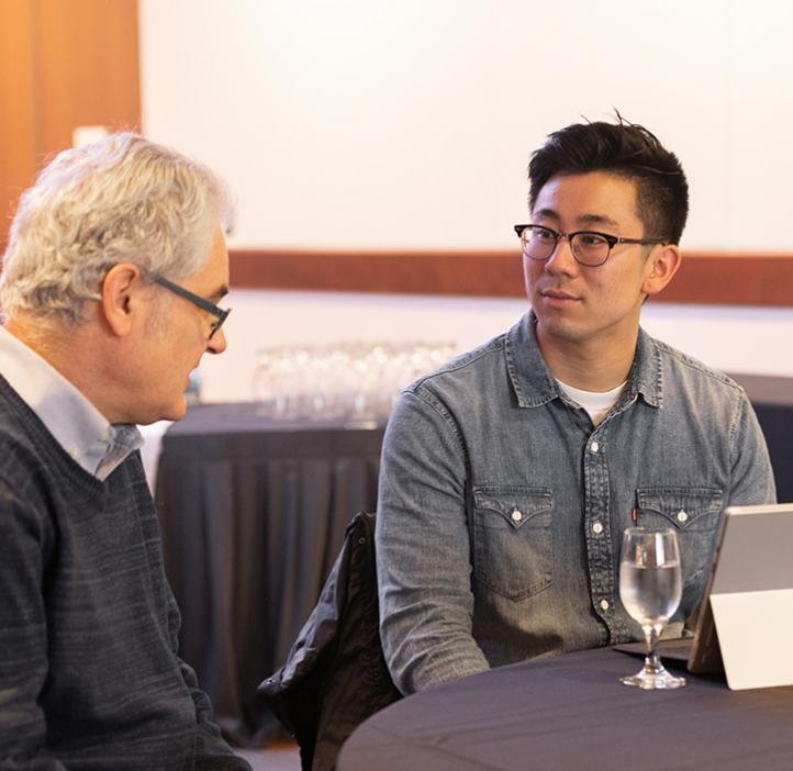 Learning Assistant talks with event attendee at table