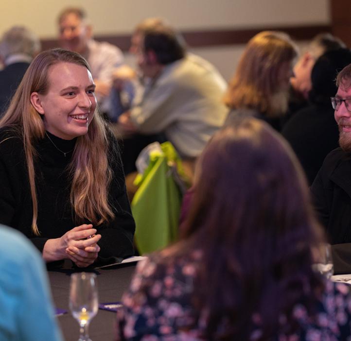 Event attendees smile and talk at table