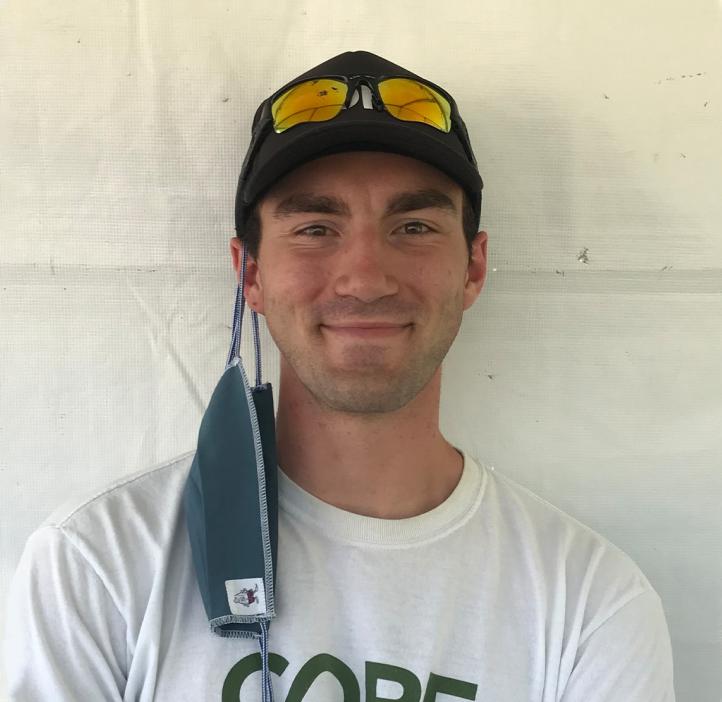Zack Bango smiling in front of a white background, wearing a CORE shirt