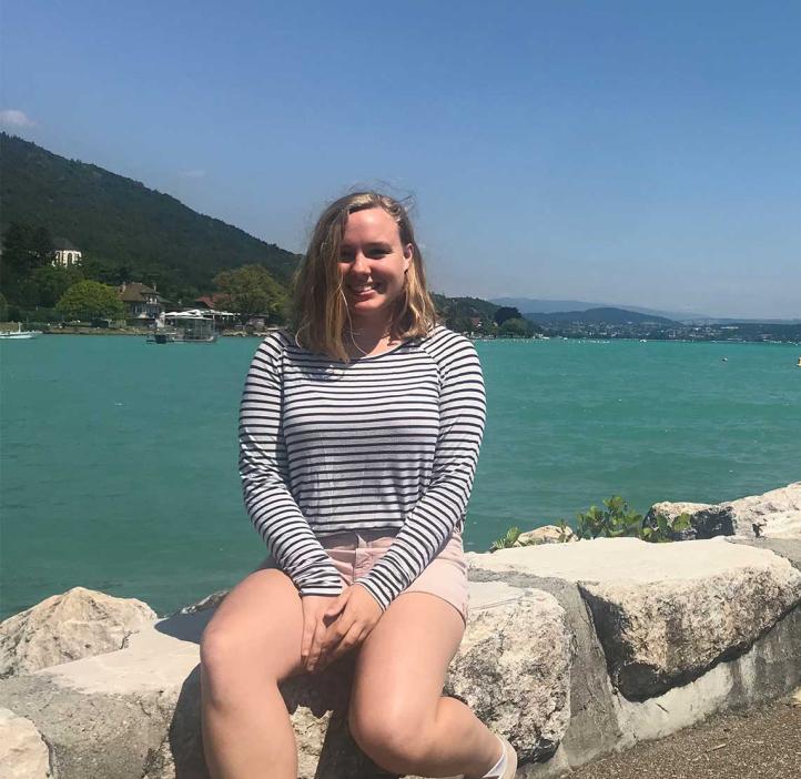 Bloom sits on a rocky ledge by the beach.