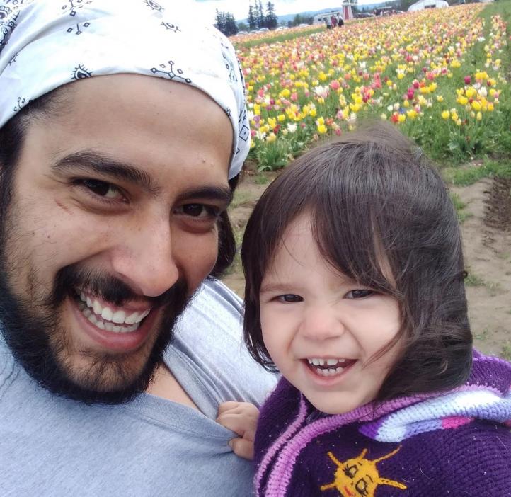 Oregon State physics graduate with daughter amid tulips.