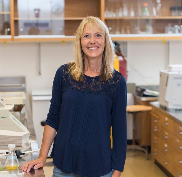 A woman standing in a lab setting smiling