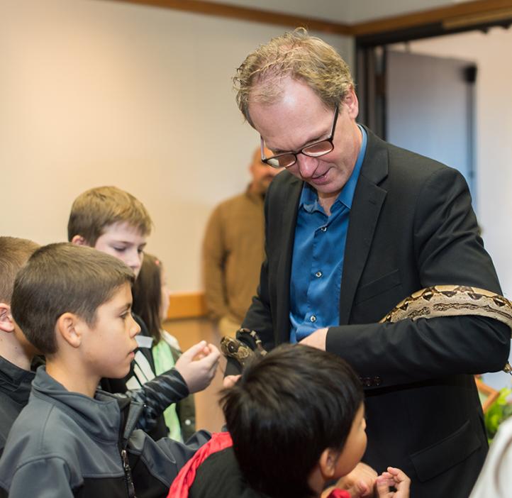 Roy Haggerty holding a large snake in front of kids during Discovery Days