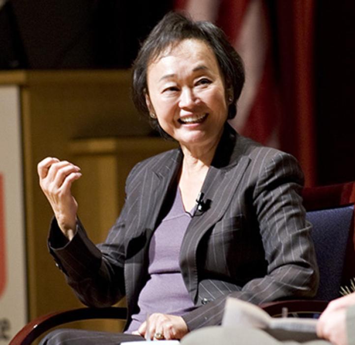 Peggy Cherng sits in a suit on stage giving a talk at an OSU event.