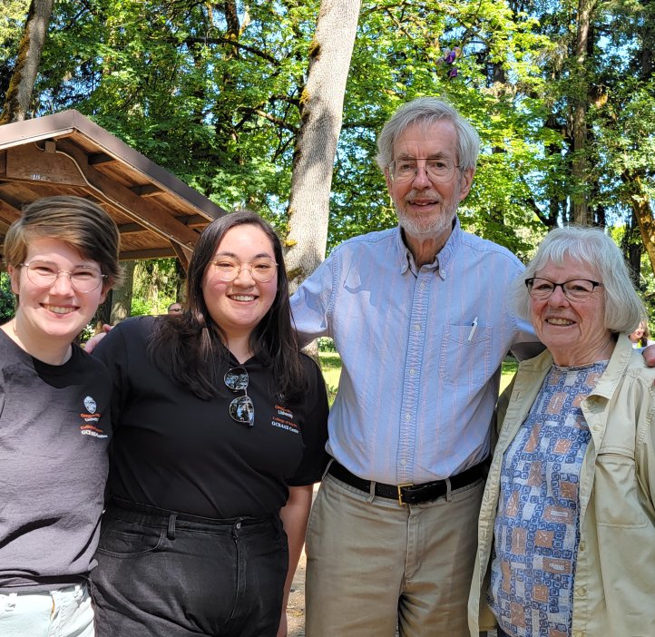 Moriah Mathis, Sarah Louie, Chris Mathews, and Kate Mathews stand outside smiling, with arms wrapped around each other.