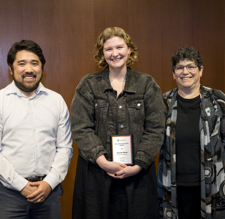 Kameron Kadooka stands with Eleanor Feingold as they present the Inclusive Excellence Award to Hannah Stuwe.