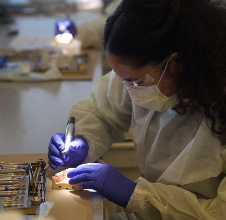 Ella Bailey wearing gloves and a mask, working with a teeth model, in a dental simulation lab at the OHSU Summit Program.