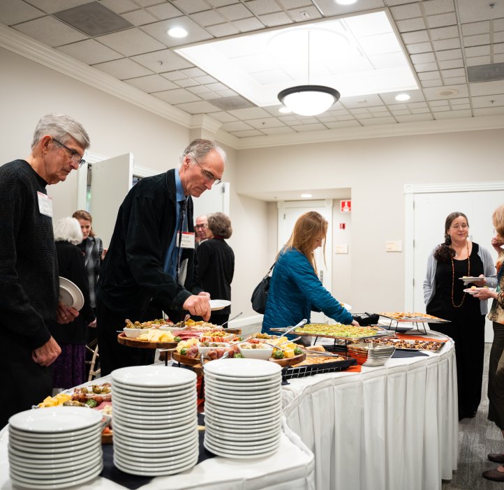 Guests gather around a buffet table filled with assorted appetizers and plates during the College of Science Alumni Awards event.