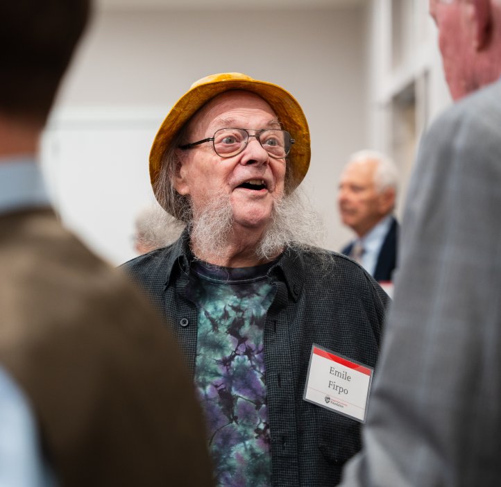 Attendee wearing a yellow hat and patterned shirt speaks with others during the College of Science Alumni Awards reception.