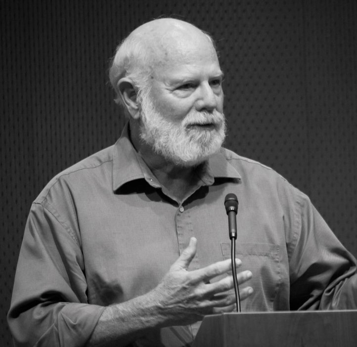 Image of Stevan J. Arnold: A male professor in short sleeve button-up shirt speaking at a podium.