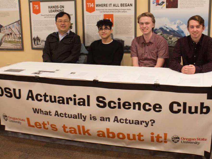 Actuarial science club members sitting at club booth.