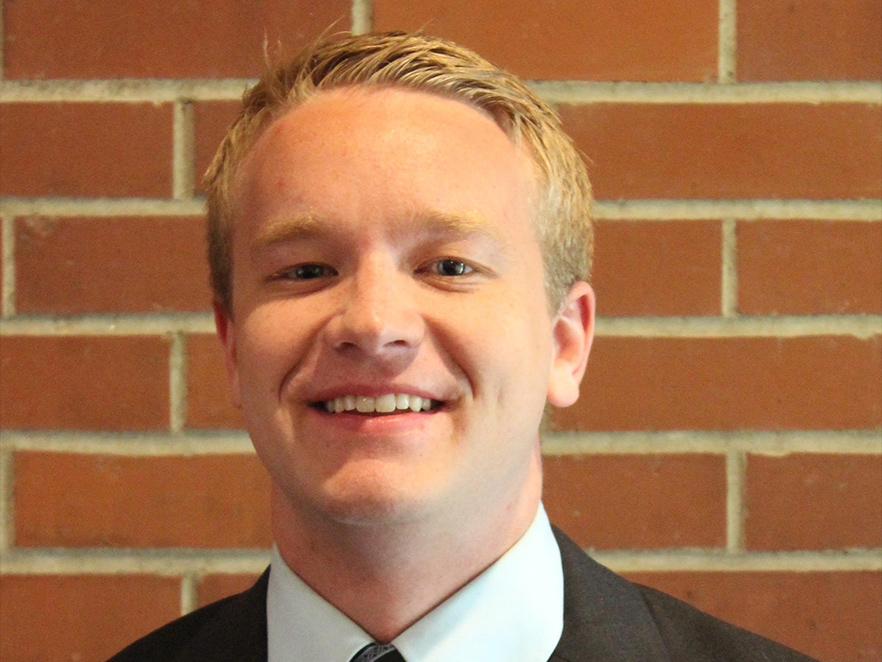 Braden Vogt, a man with short blonde hair in front of a brick background.