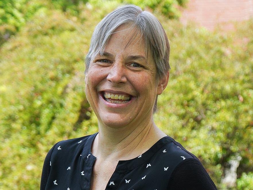 Kari van Zee smiles broadly in a campus headshot
