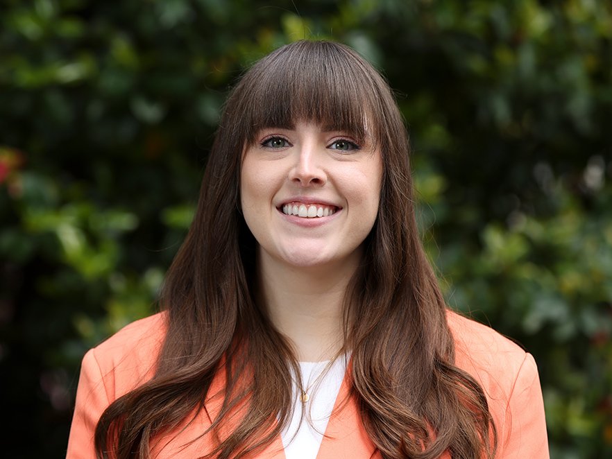 Smiling headshot of Rachel Palmer on campus in a bright blazer