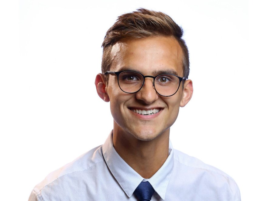 Smiling headshot of a man in a button up and tie